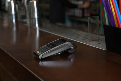 Photo of Credit card machine for non cash payment on wooden counter in cafe