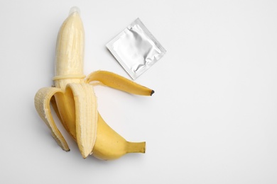 Photo of Banana with condom on white background, top view. Safe sex