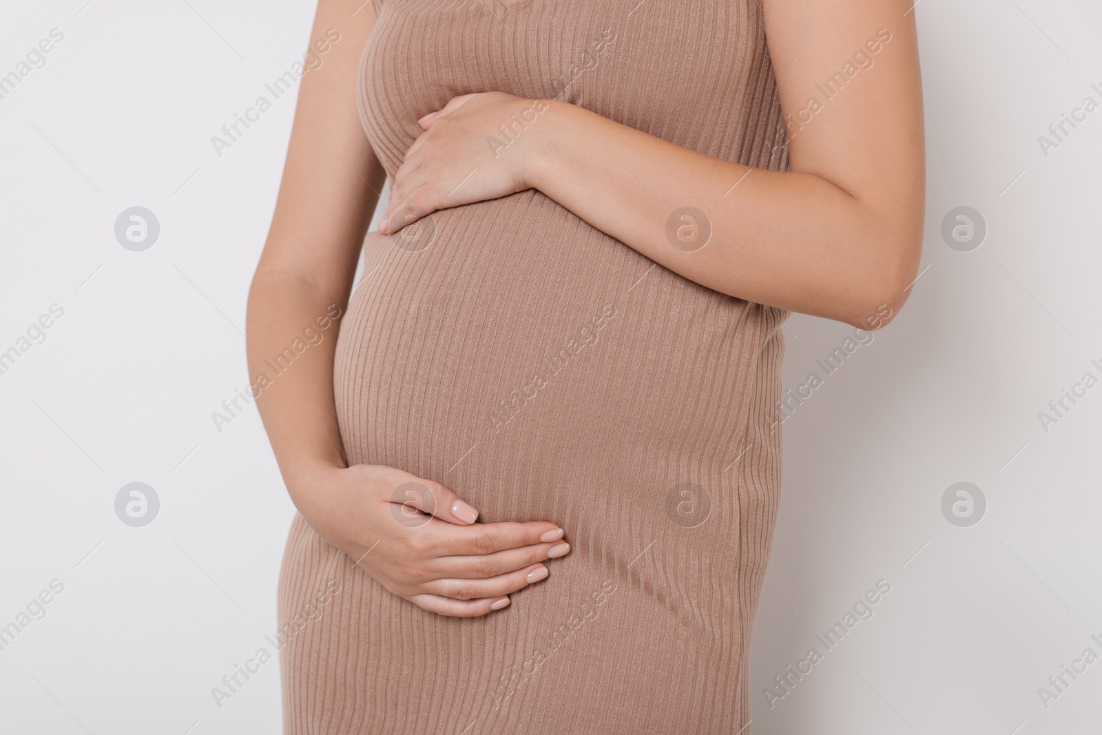 Photo of Pregnant woman in beige dress on white background, closeup