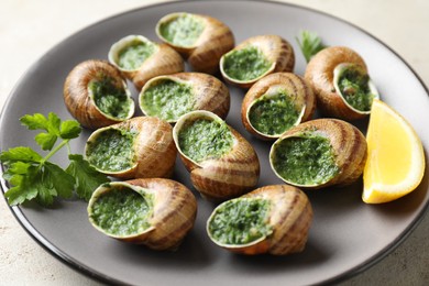 Delicious cooked snails with parsley and lemon on light table, closeup