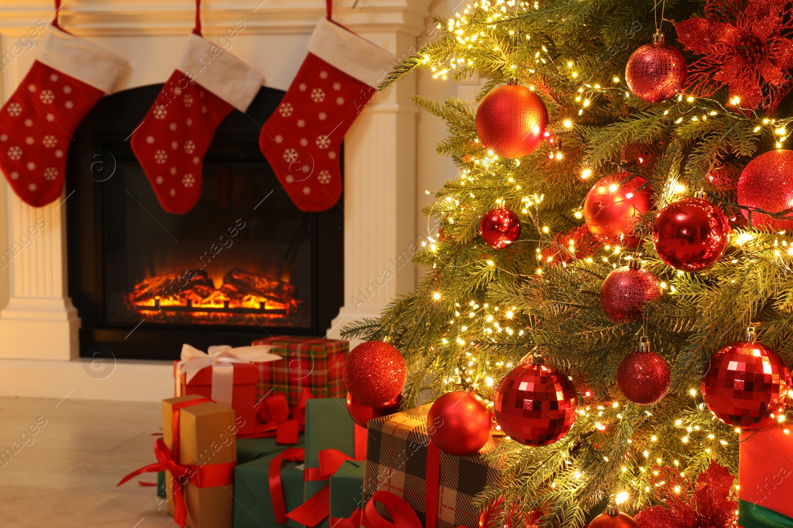 Photo of Many gift boxes under decorated Christmas tree and fireplace indoors