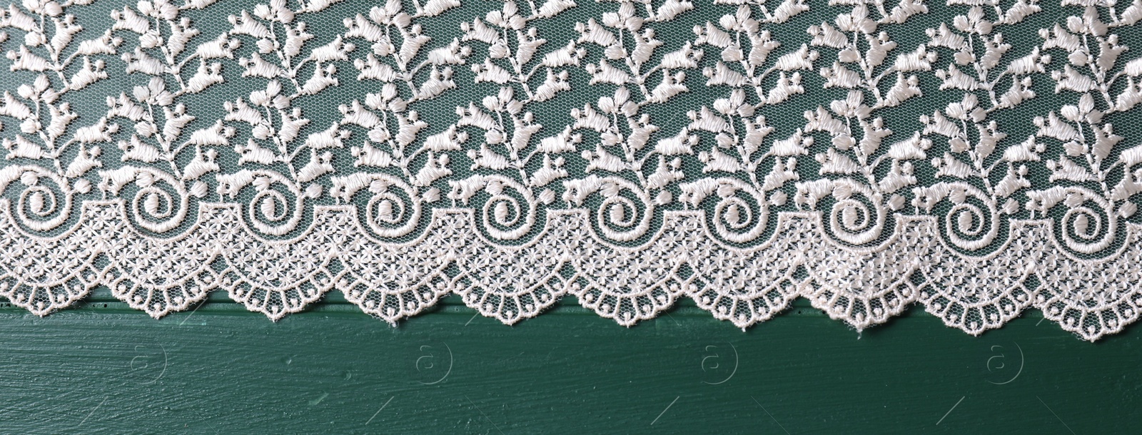 Photo of Beige lace on green wooden table, top view