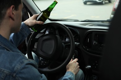 Man with bottle of beer driving car, closeup. Don't drink and drive concept