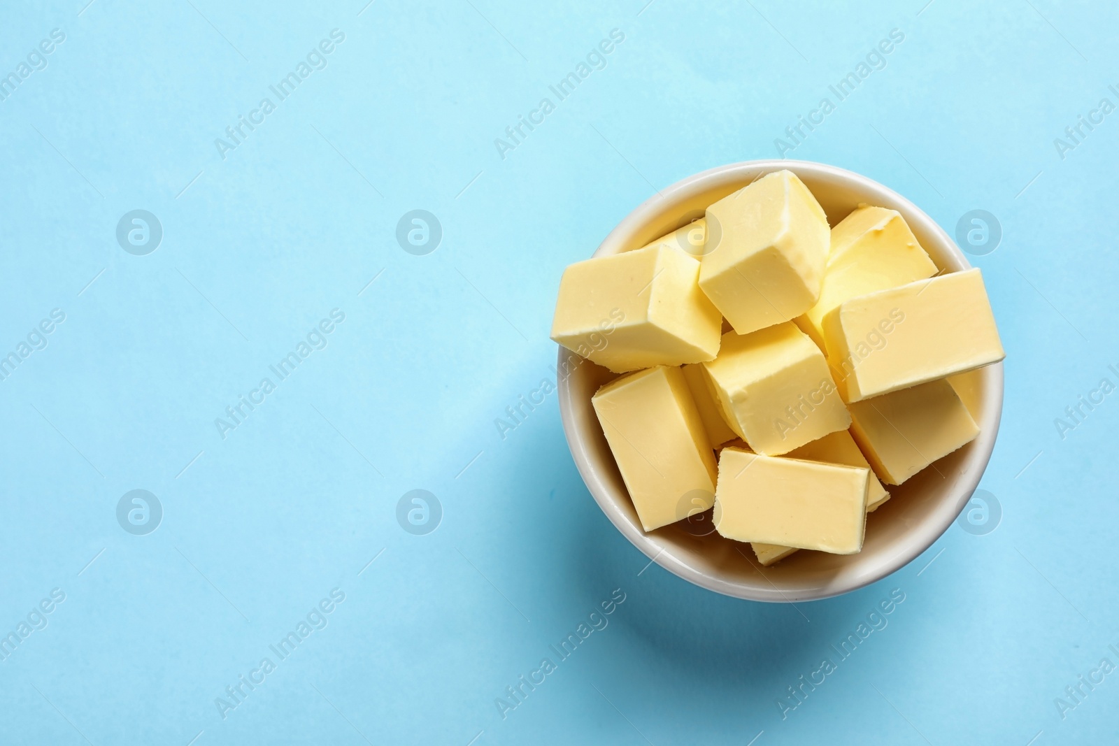 Photo of Bowl with fresh butter on color background, top view. Space for text