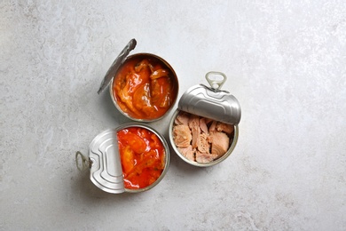 Photo of Tin cans with fish on grey table, flat lay
