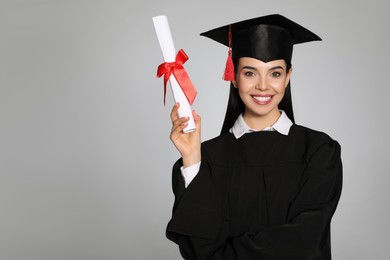 Photo of Happy student with graduation hat and diploma on grey background. Space for text