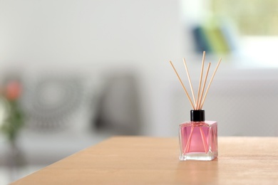 Photo of Aromatic reed air freshener on table indoors