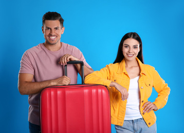 Happy couple with suitcase for summer trip on blue background. Vacation travel