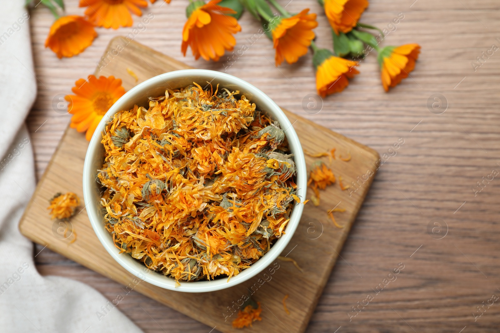 Photo of Dry and fresh calendula flowers on wooden table, flat lay. Space for text