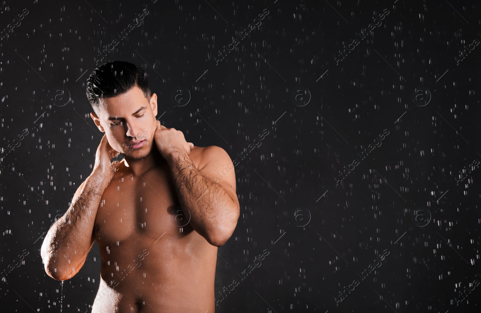 Photo of Man washing hair while taking shower on black background. Space for text