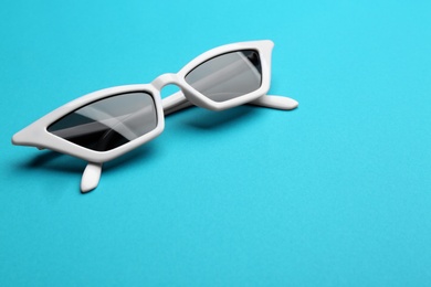 Photo of Stylish sunglasses on blue background, space for text. Fashionable accessory