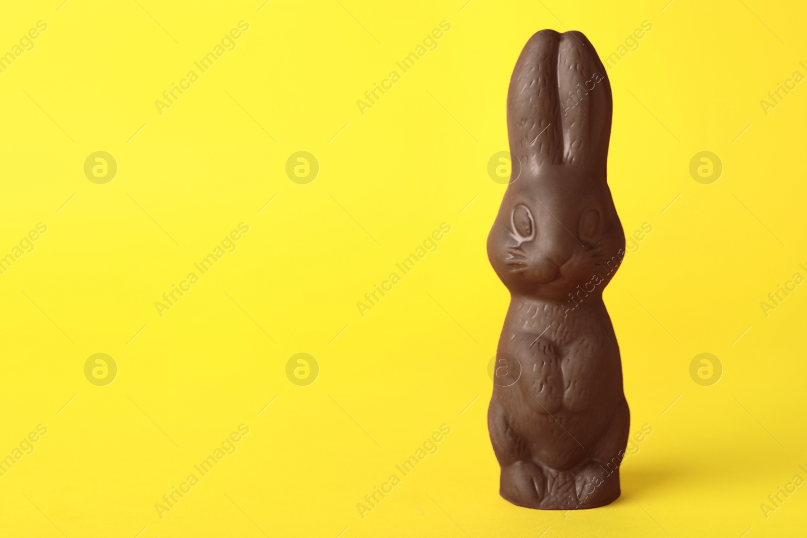 Photo of Chocolate bunny on yellow background, space for text. Easter celebration