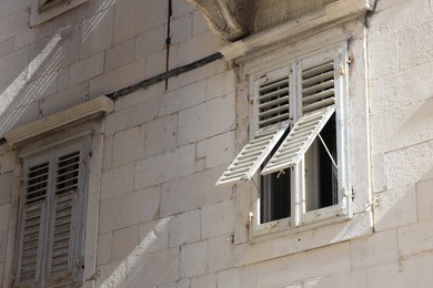 Photo of Windows with wooden shutters on wall of old residential building
