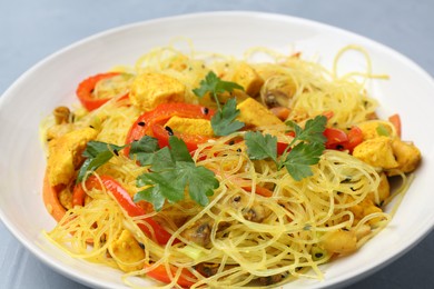 Photo of Stir-fry. Delicious cooked noodles with chicken and vegetables in bowl on gray table, closeup