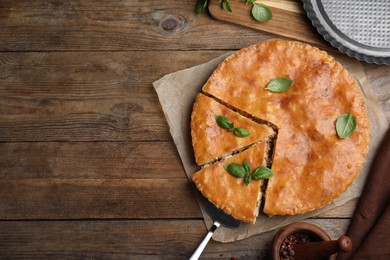 Photo of Delicious pie with meat and basil on wooden table, flat lay. Space for text