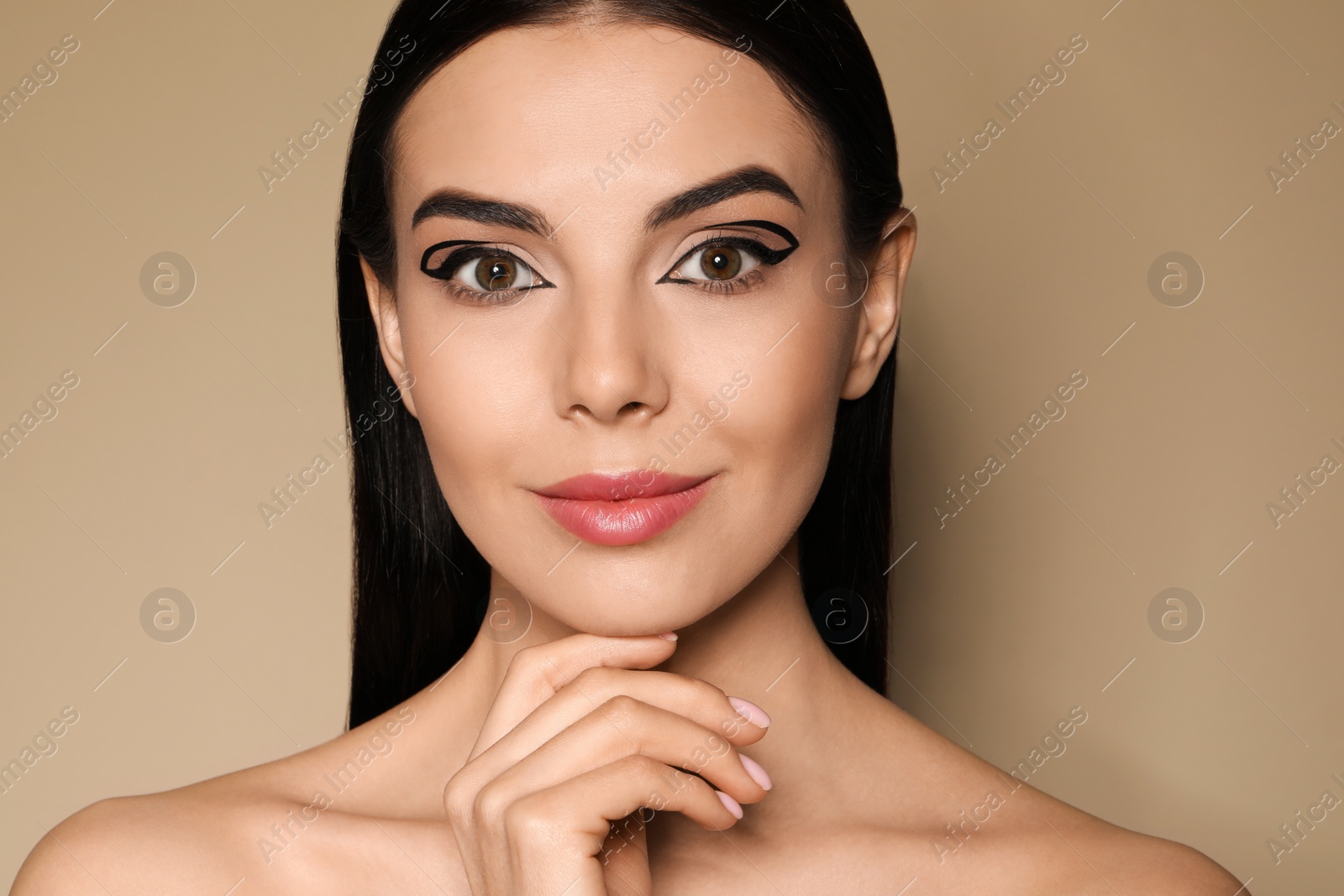 Photo of Beautiful woman with black eyeliner on beige background