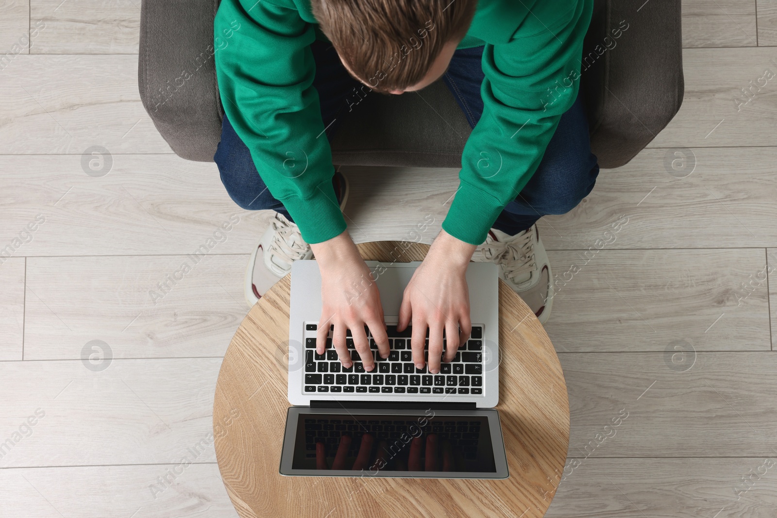 Photo of Man working with laptop at wooden table, top view. Space for text