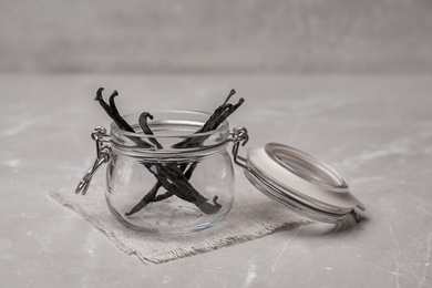 Photo of Jar with aromatic vanilla sticks on grey background