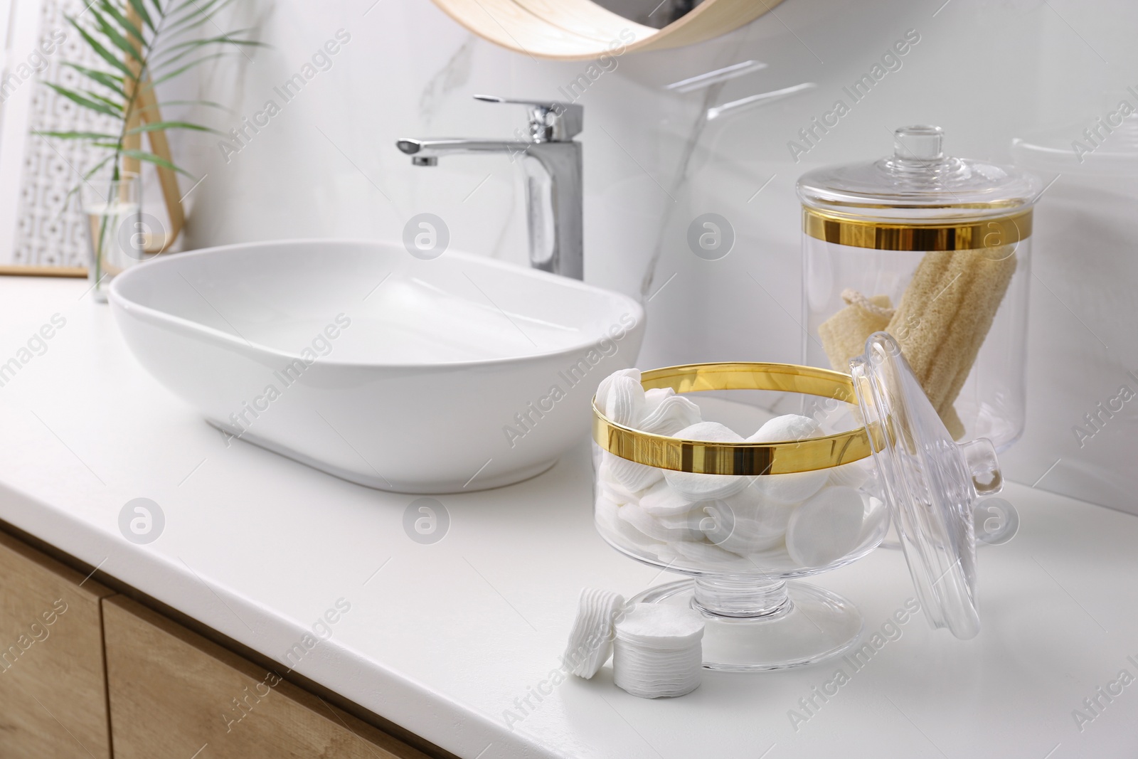 Photo of Glass jars with cotton pads and loofahs on table in bathroom