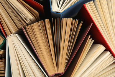 Photo of Many different hardcover books on dark background, top view