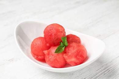 Plate of watermelon balls with mint on white wooden table