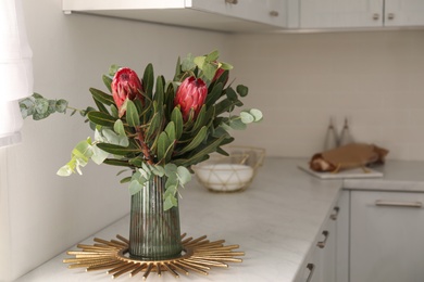 Bouquet with beautiful protea flowers on countertop in kitchen, space for text. Interior design