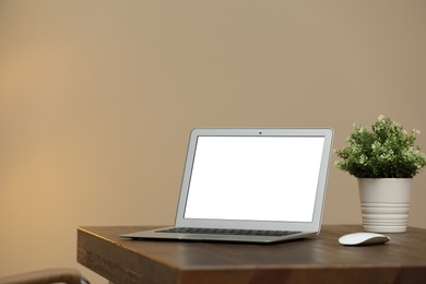 Photo of Laptop with blank screen on table indoors. Space for text