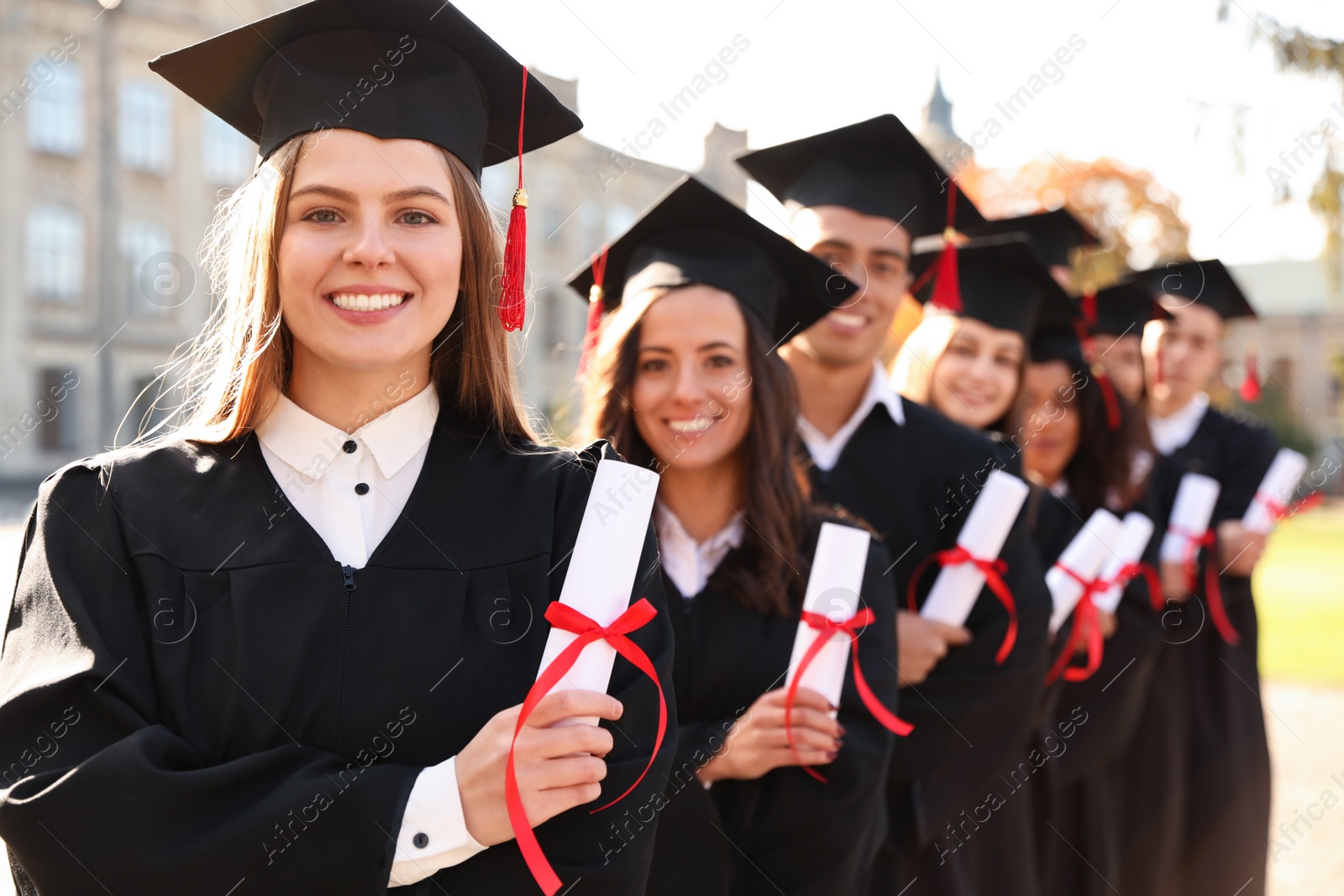 Photo of Happy students with diplomas outdoors. Graduation ceremony