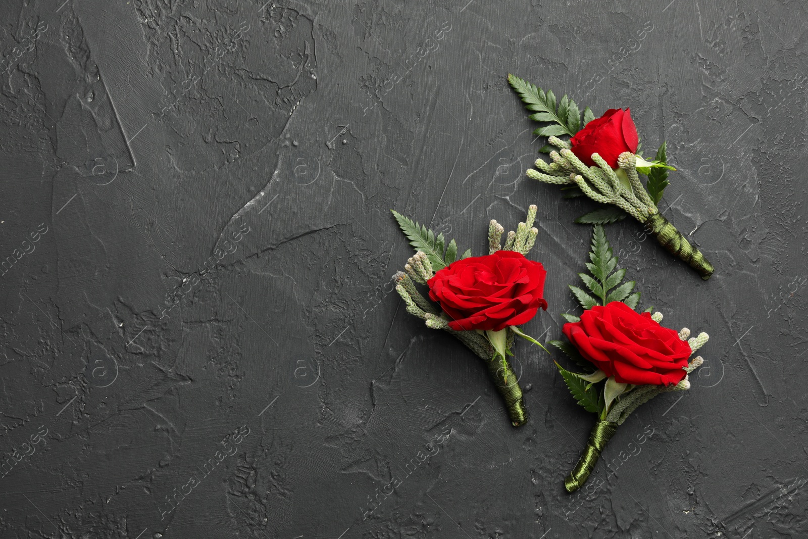 Photo of Many stylish red boutonnieres on black table, flat lay. Space for text