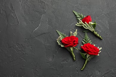 Photo of Many stylish red boutonnieres on black table, flat lay. Space for text