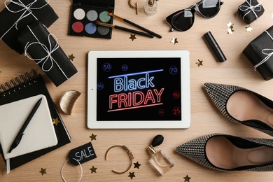 Photo of Flat lay composition with tablet, gifts and accessories on wooden background. Black Friday sale