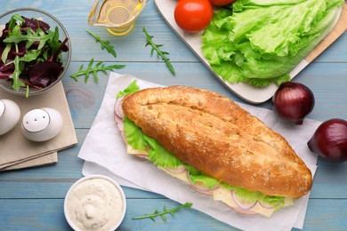 Photo of Delicious sandwich and fresh ingredients on light blue wooden table, flat lay