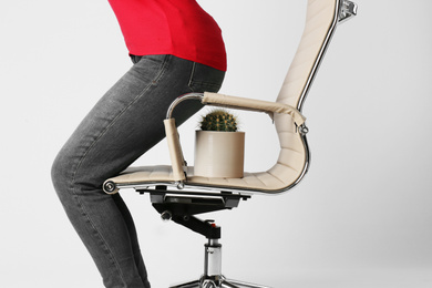 Woman sitting down on chair with cactus against white background, closeup. Hemorrhoids concept