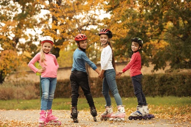 Photo of Cute children roller skating in autumn park