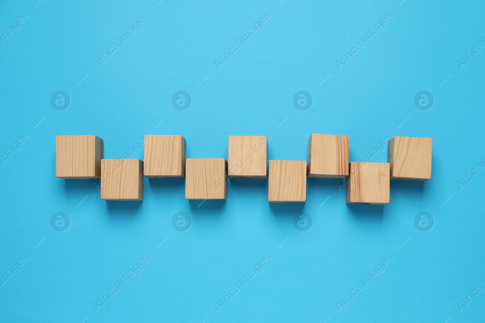 Photo of Wooden cubes on light blue background, flat lay
