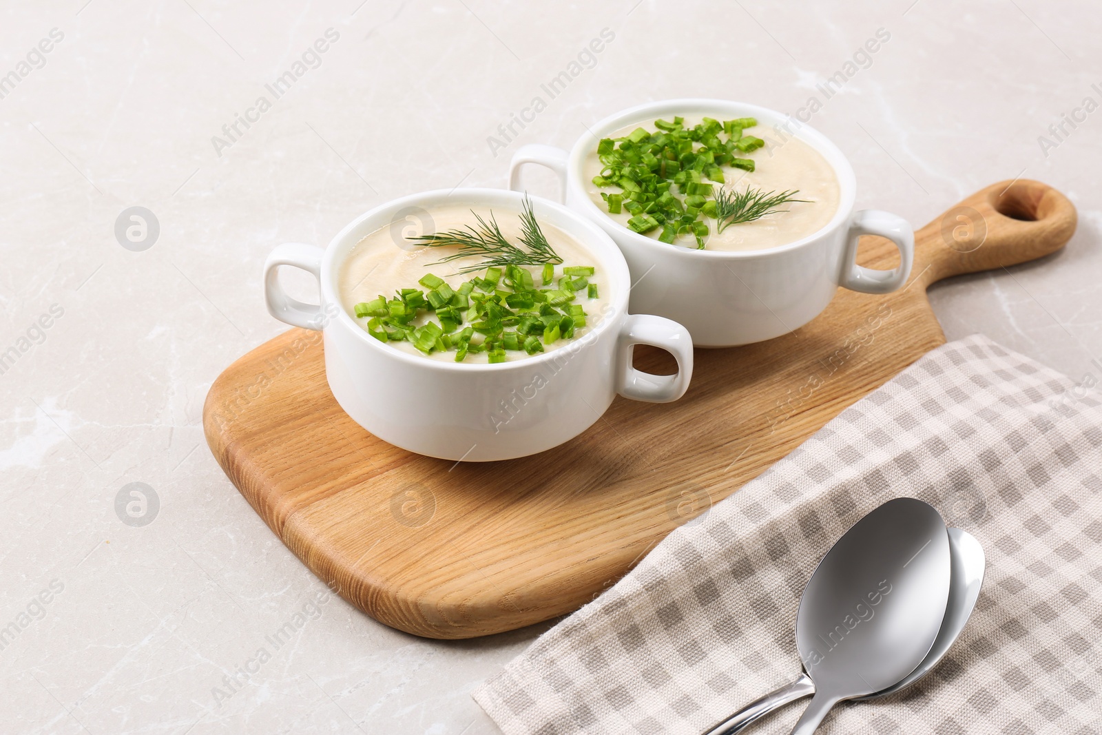 Photo of Bowls with tasty creamy soup of parsnip served on light grey background