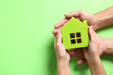 Photo of Couple holding house model on light green background, top view. Space for text