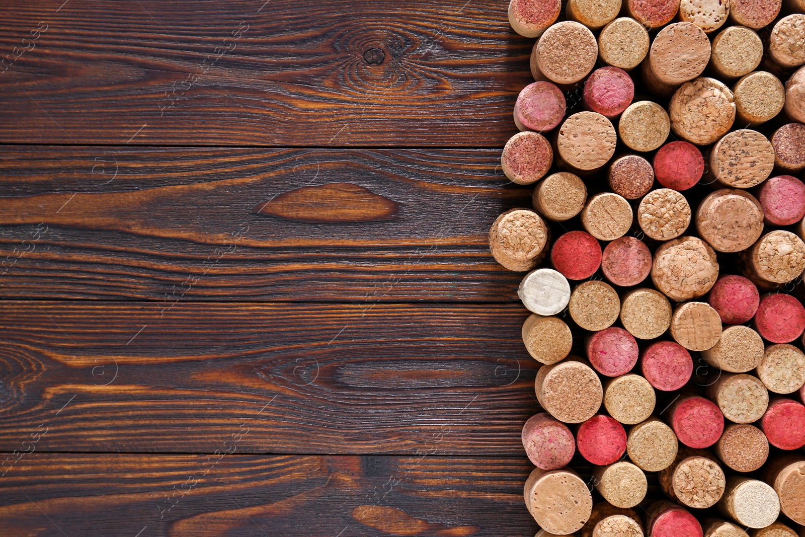 Photo of Many corks of wine bottles on wooden table, top view. Space for text