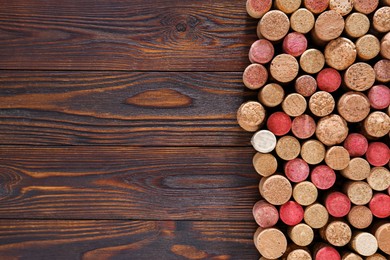 Many corks of wine bottles on wooden table, top view. Space for text