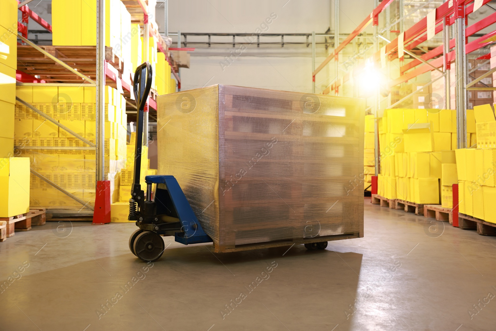 Image of Modern manual forklift with wrapped wooden pallets in warehouse