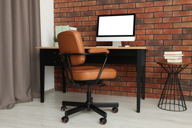 Stylish office interior with comfortable chair, desk and computer