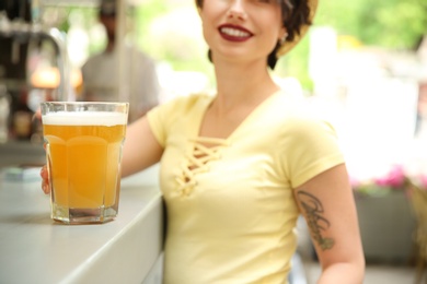 Photo of Young woman with glass of cold beer near bar counter