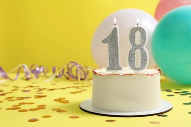 Photo of Coming of age party - 18th birthday. Delicious cake with number shaped candles on yellow background, space for text
