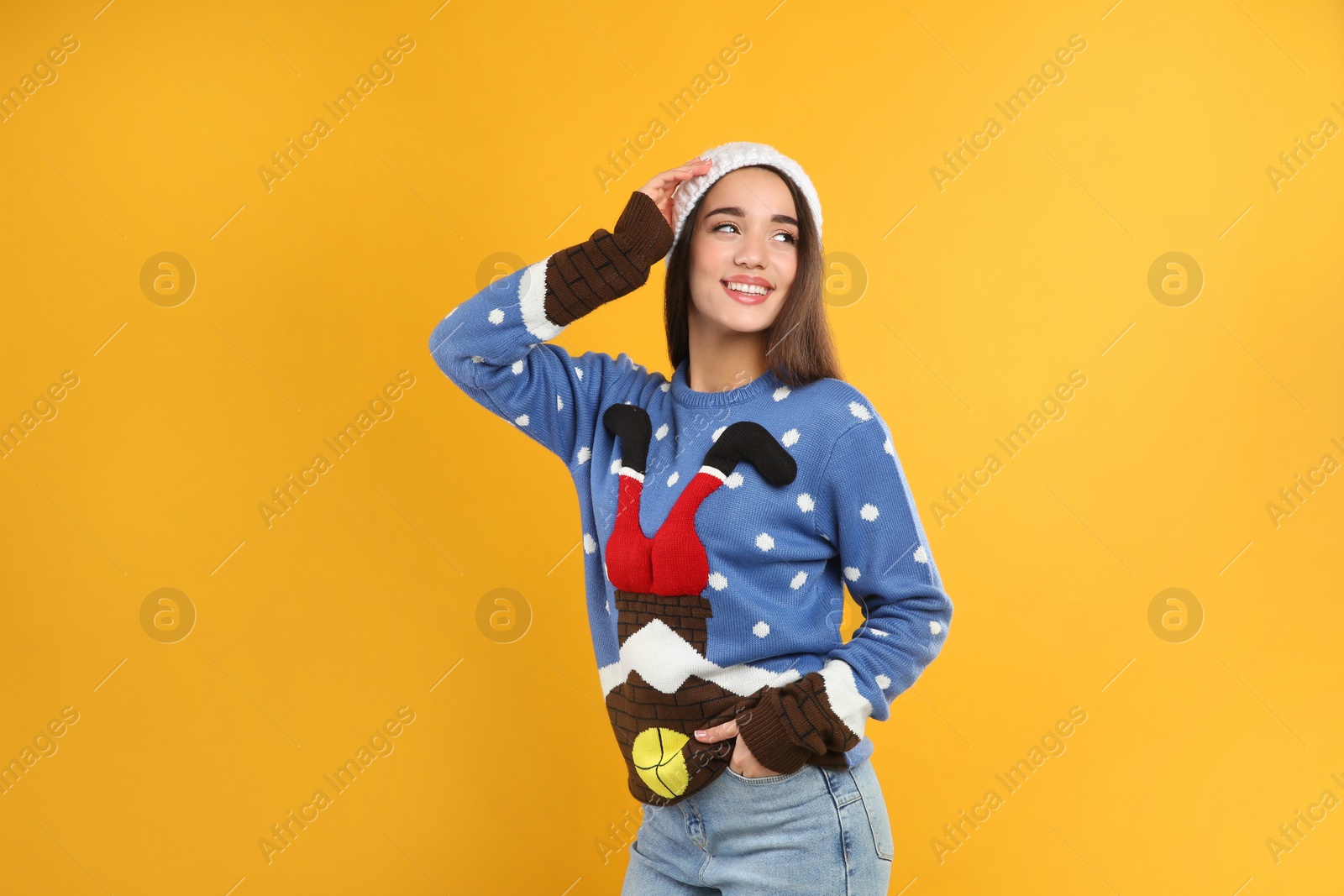 Photo of Young woman in Christmas sweater and hat on yellow background