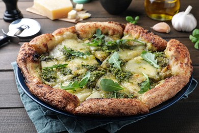 Photo of Delicious pizza with pesto, cheese and arugula on wooden table, closeup