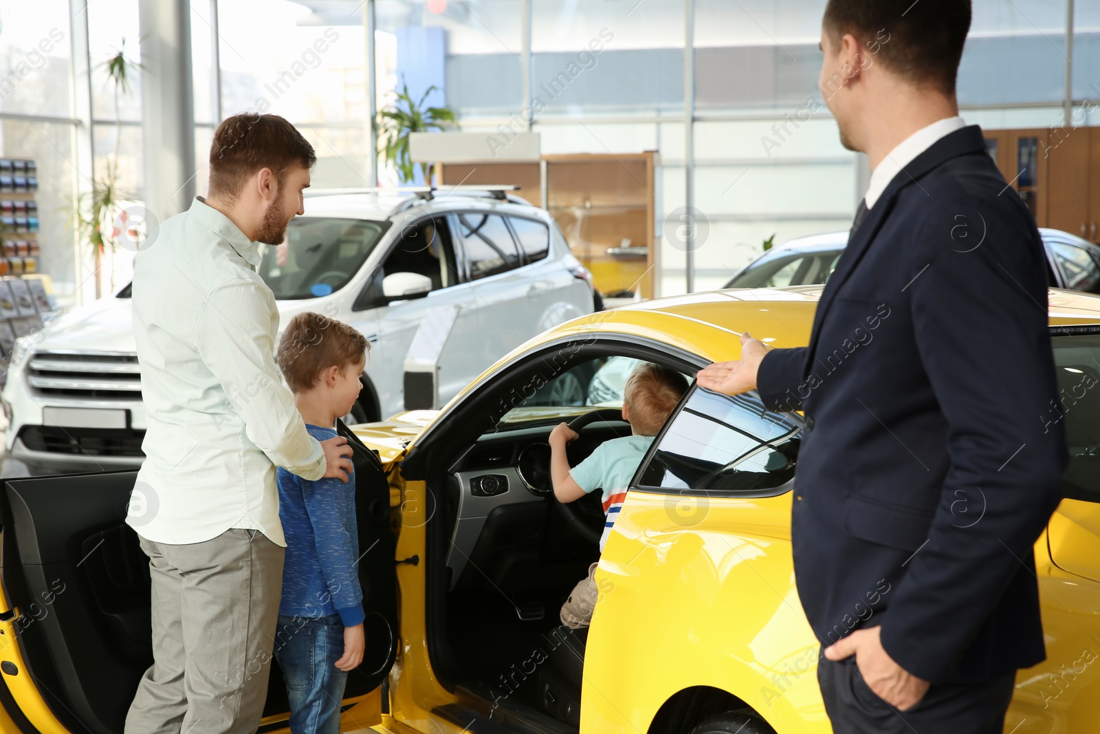 Photo of Young family choosing new car with salesman in salon