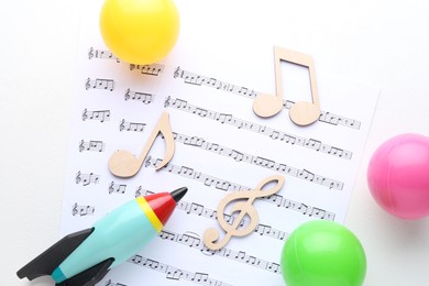 Wooden notes, music sheets and toys on white background, top view. Baby song concept