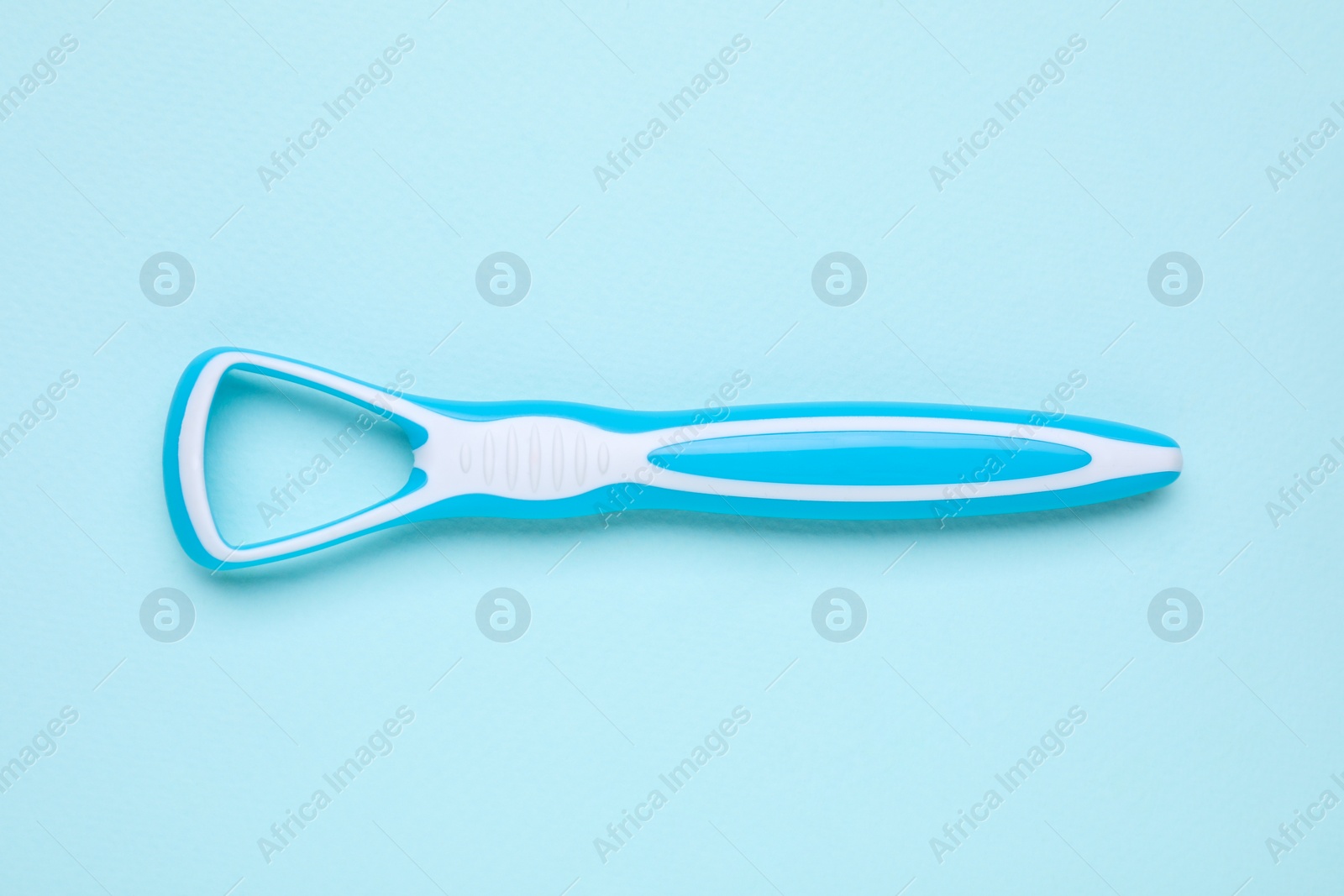 Photo of Tongue cleaner on light blue background, top view