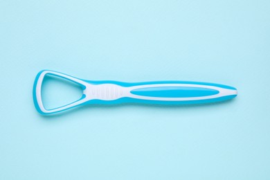 Photo of Tongue cleaner on light blue background, top view