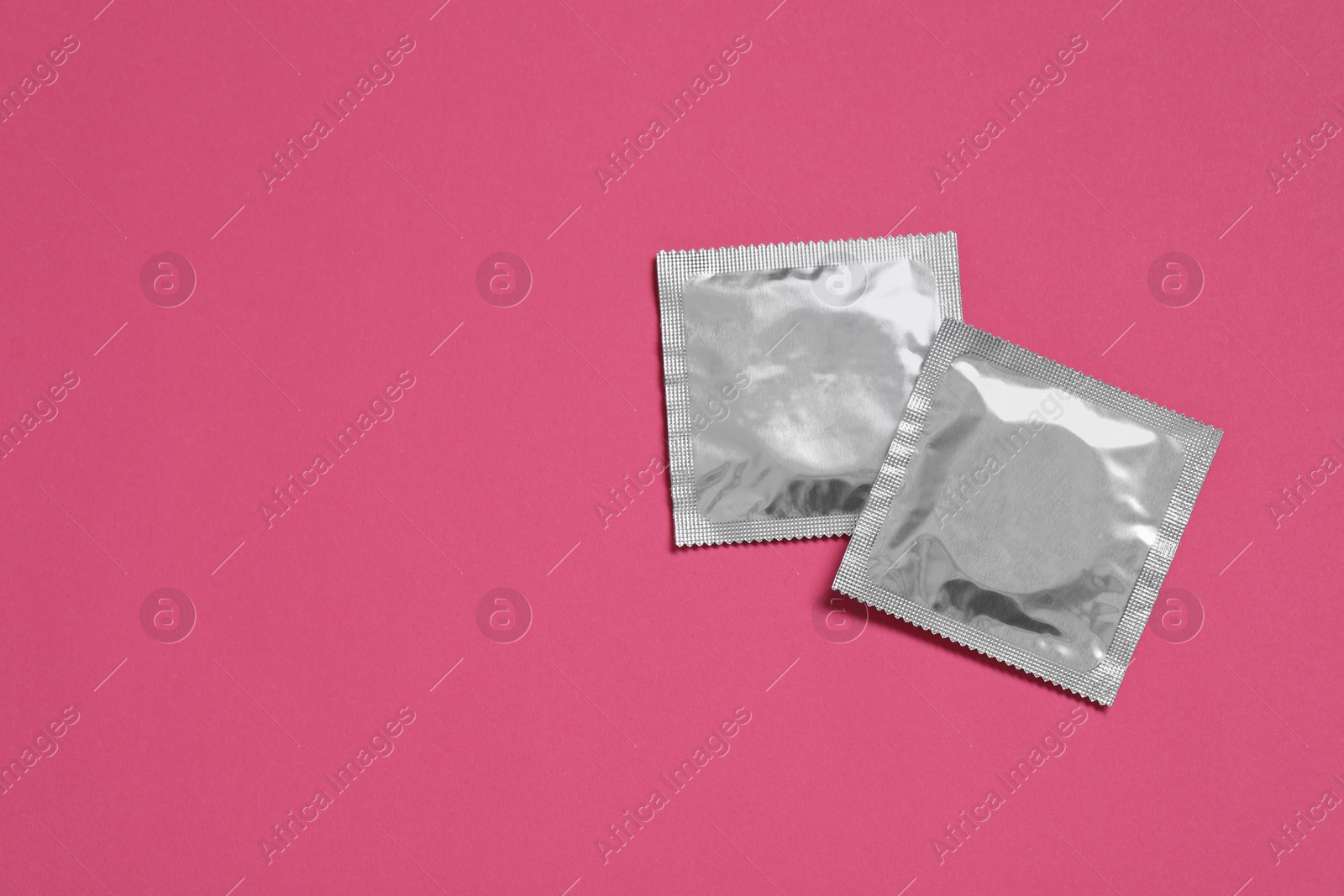 Photo of Condom packages on pink background, flat lay and space for text. Safe sex